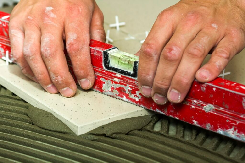 Ceramic tiles and tools for tiler. Worker hand installing floor tiles.