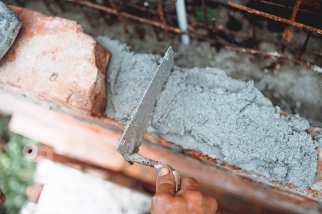 Professional worker using pan knife for building old brick walls with cement and mortar