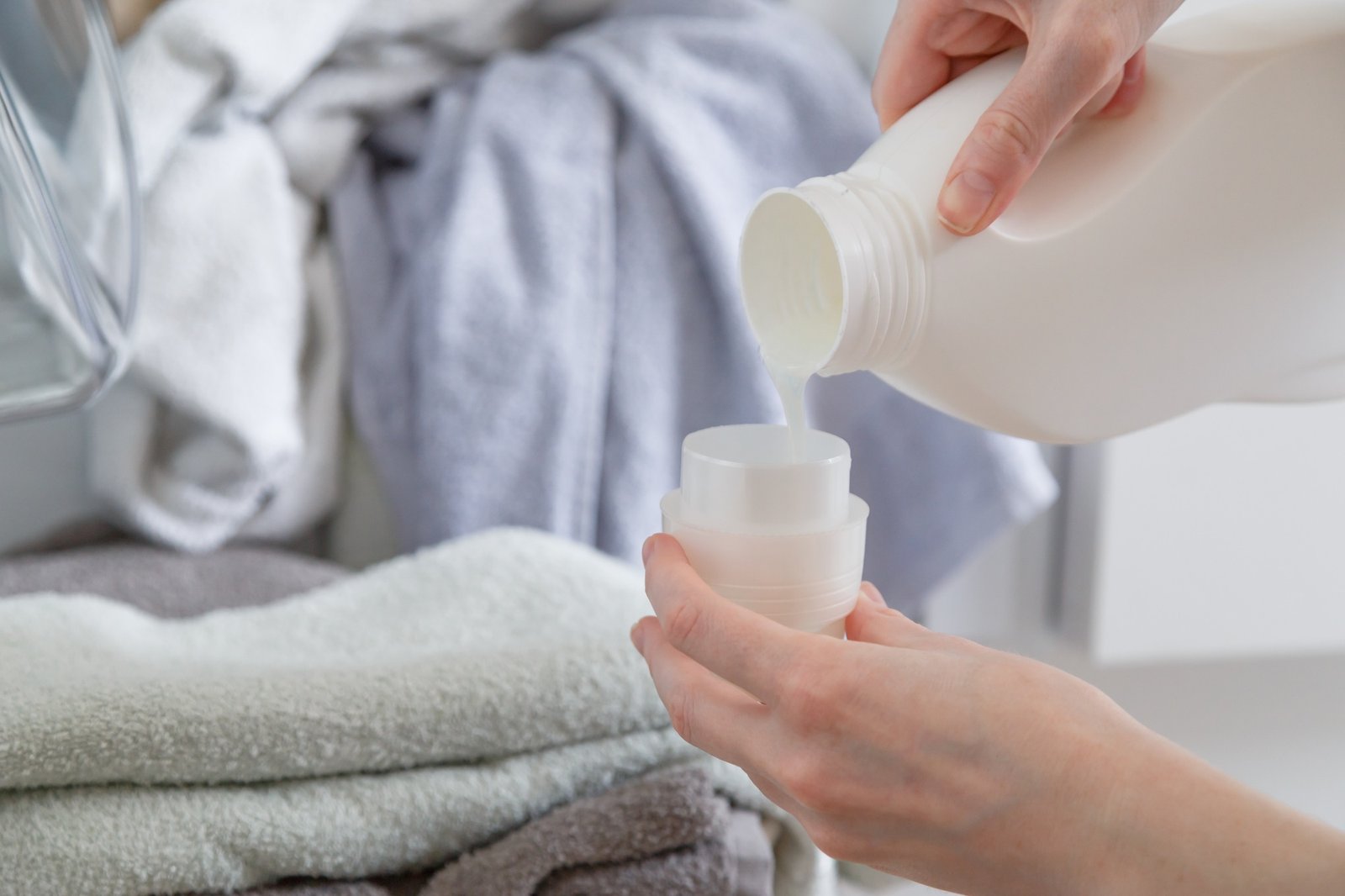 Close up of female hands pouring liquid laundry detergent into cap